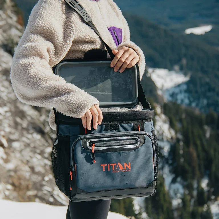 person holding Titan cooler on snowy mountain
