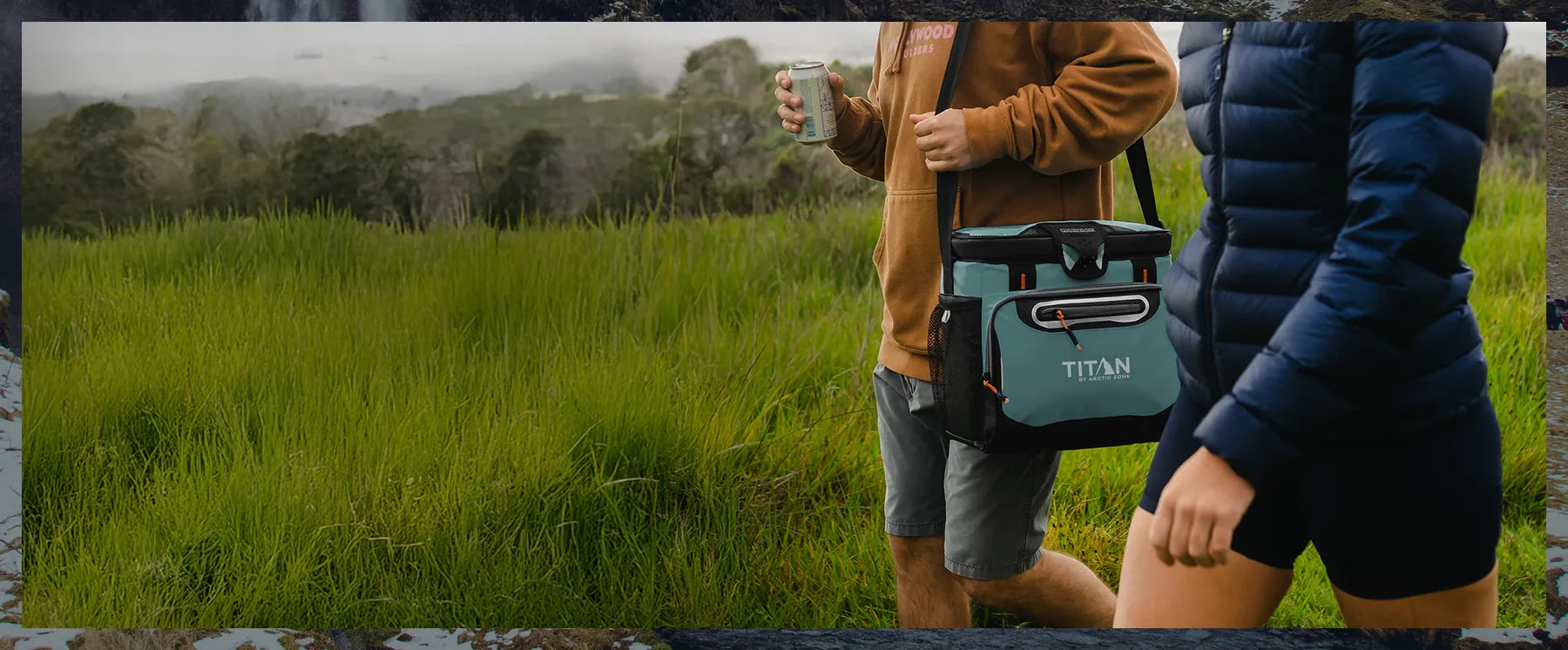 couple walking through mountain field with titan cooler